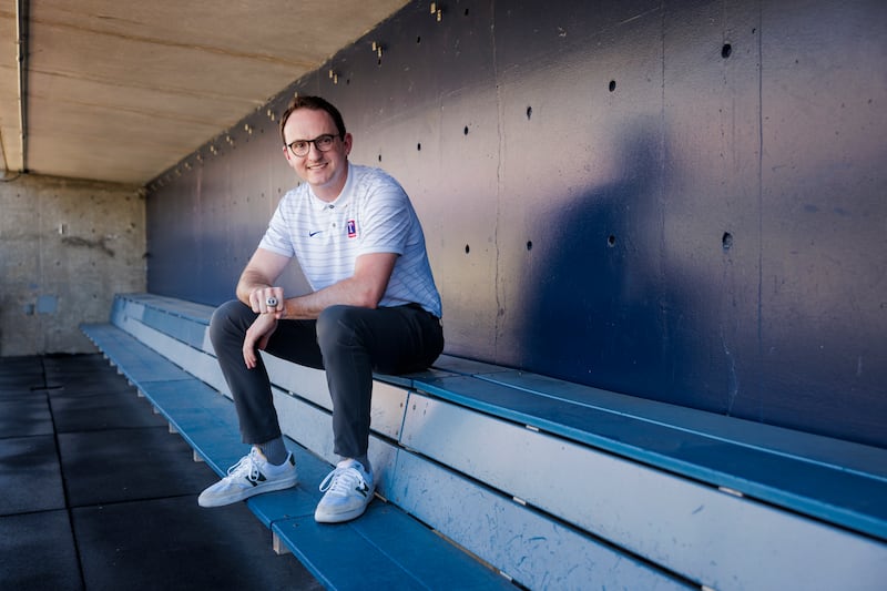 Will Melville, a Latter-day Saint and BYU graduate student, sits in a baseball dugout.
