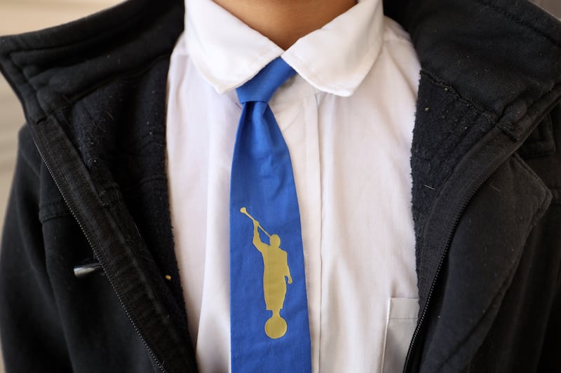 A young boy wears a tie featuring the Angel Moroni statue.