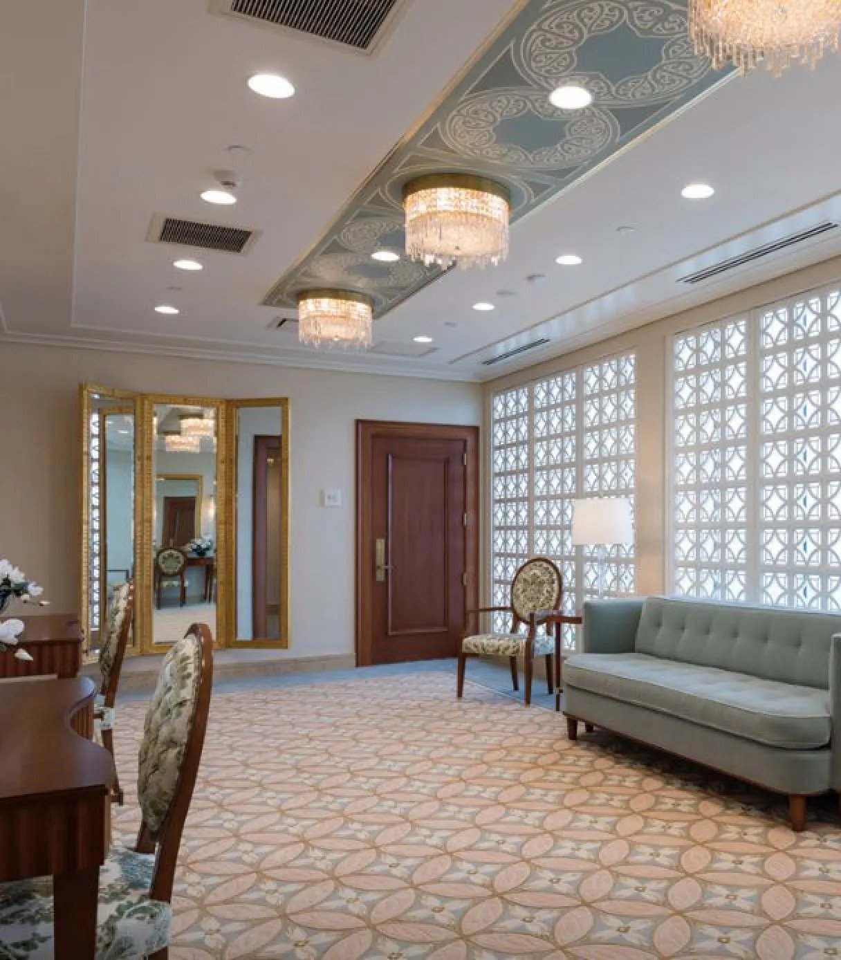 A white room with a rectangular mirror above a dark-wood desk.