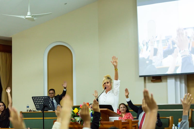 Sister Tamara W. Runia raises her hands with the youth in a chapel in Managua, Nicaragua.